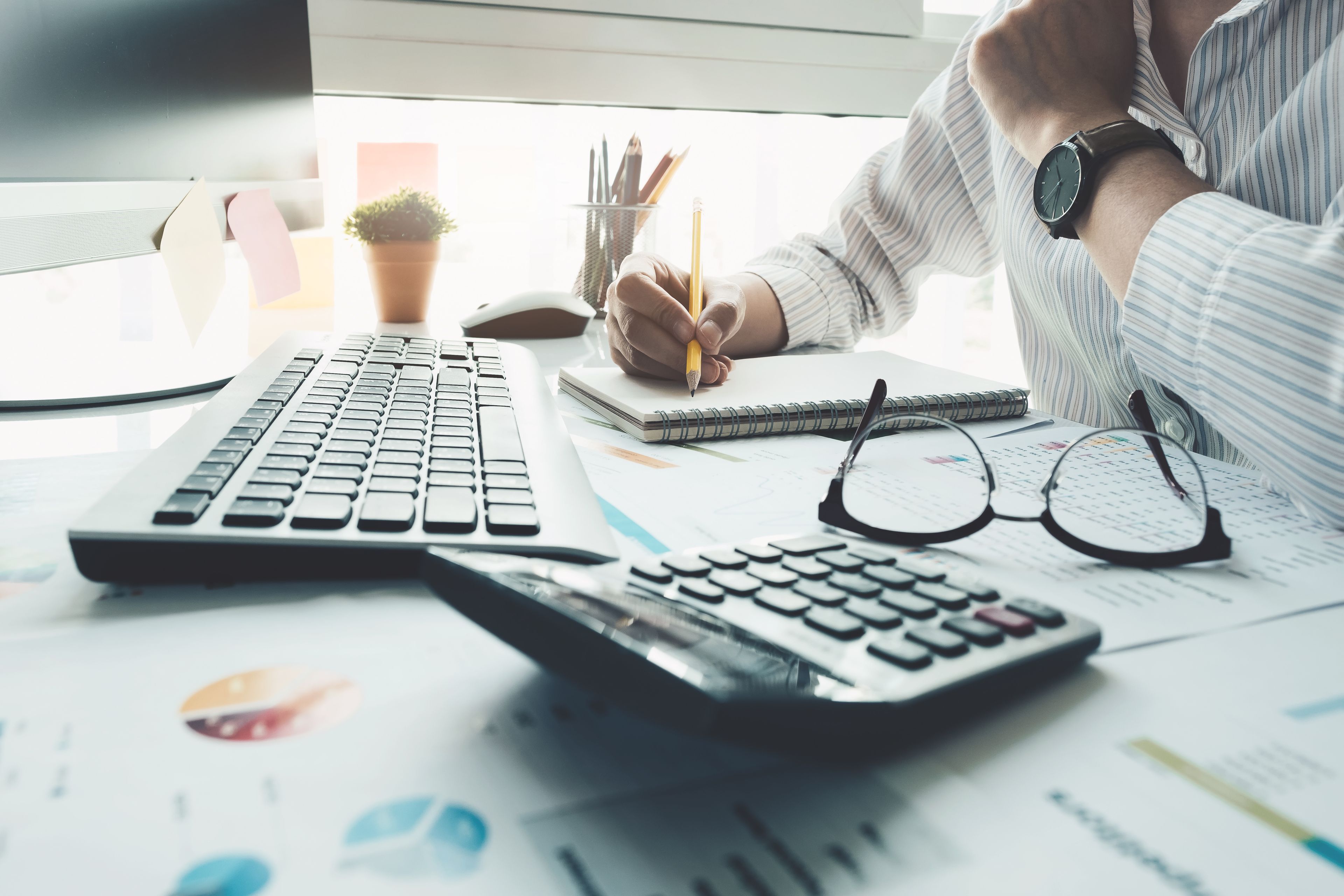 Moderner Arbeitsplatz mit Unterlagen, Tastatur und Taschenrechner bei kaufmännischer Büroarbeit und Finanzplanung.