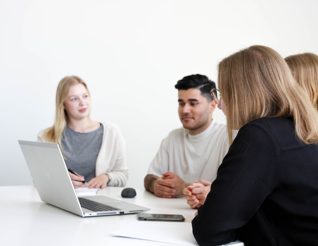 4 Menschen tauschen sich an einem Laptop über ein Thema aus.
