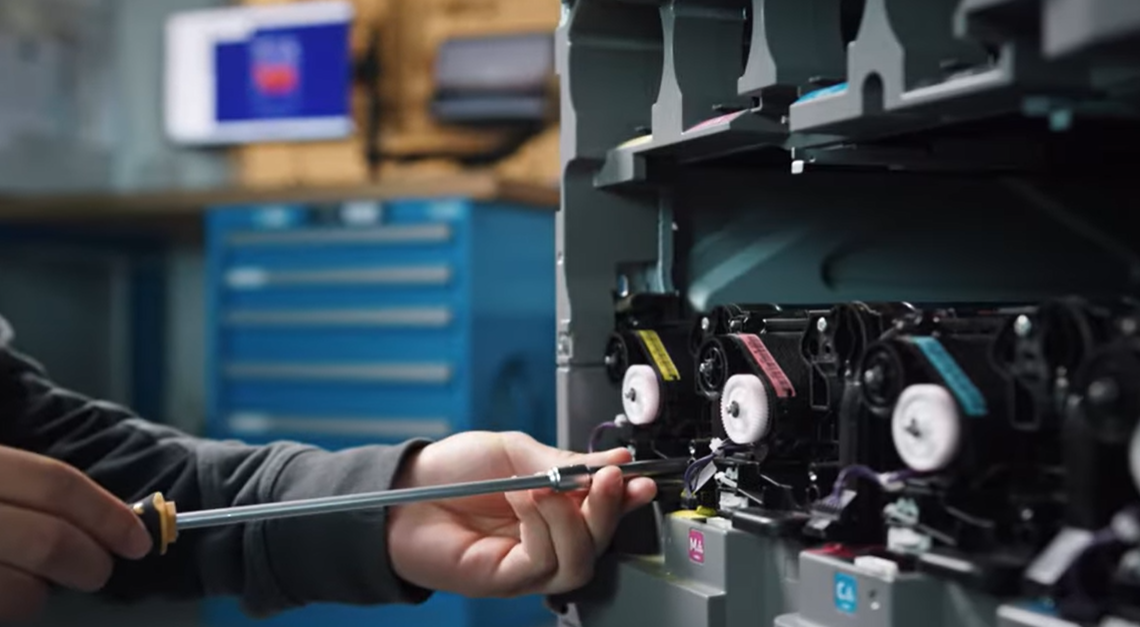 Techniker bei der Wartung und Feinjustierung eines modernen Drucksystems in der Werkstatt.