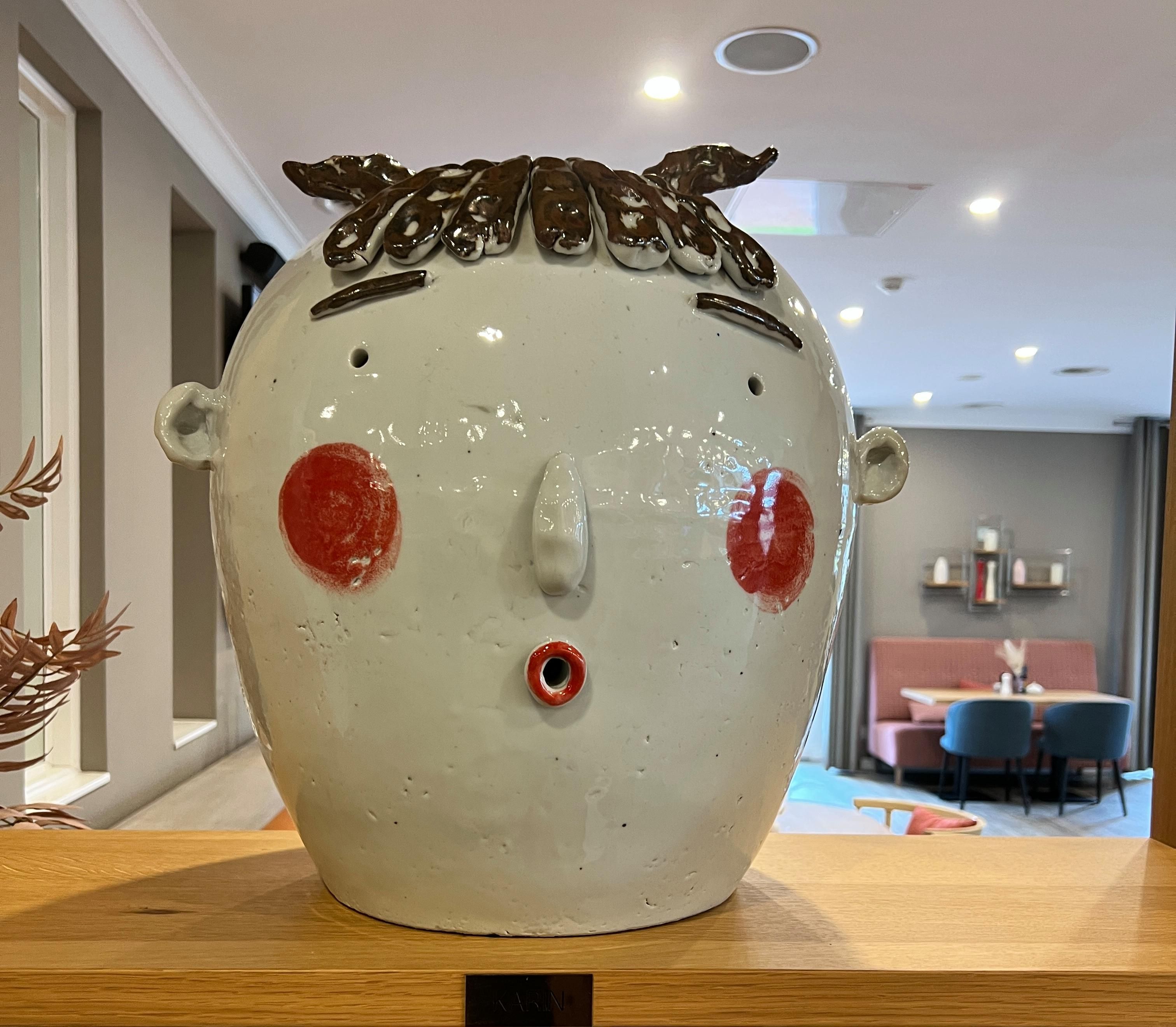 Dekorative Keramikskulptur in Form eines Gesichts als stilvolles Designelement in modernem Innenraum.
